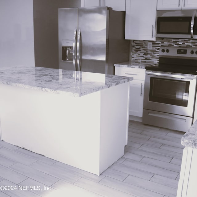 kitchen with white cabinets, light stone countertops, appliances with stainless steel finishes, and tasteful backsplash