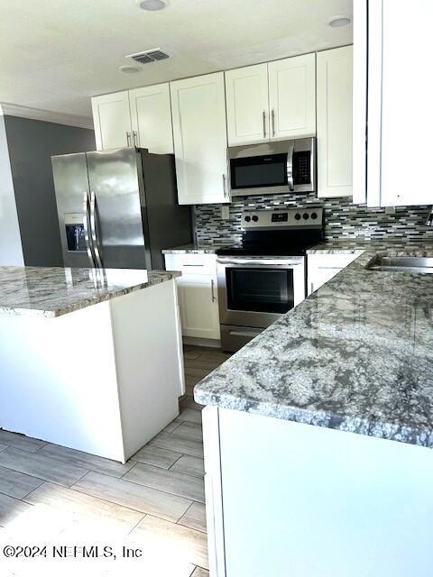 kitchen featuring white cabinets, sink, appliances with stainless steel finishes, tasteful backsplash, and light stone counters