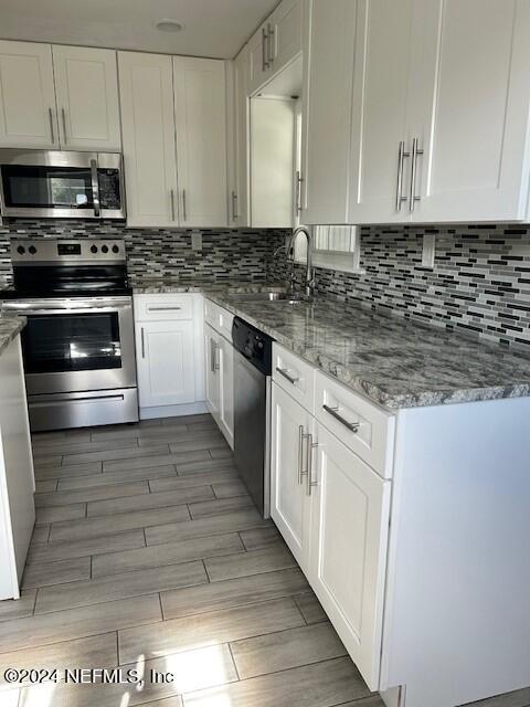 kitchen featuring white cabinets, stainless steel appliances, light stone countertops, and sink