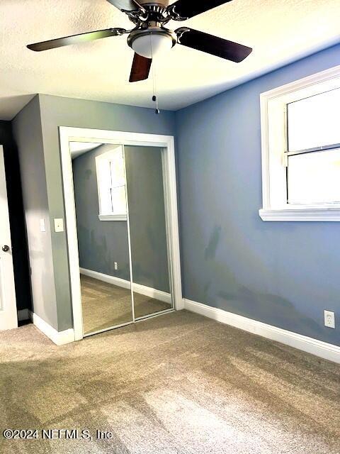 unfurnished bedroom featuring ceiling fan, a closet, and carpet floors