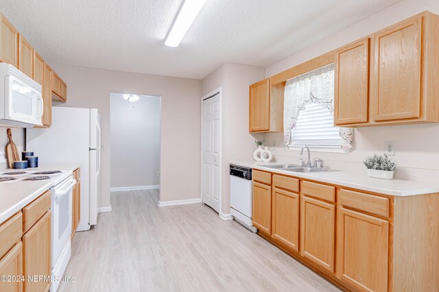 kitchen featuring a textured ceiling, white appliances, light brown cabinets, and sink