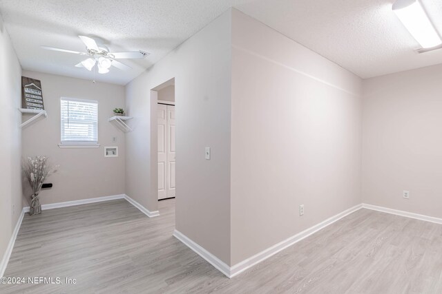 laundry room with ceiling fan, light hardwood / wood-style floors, and a textured ceiling