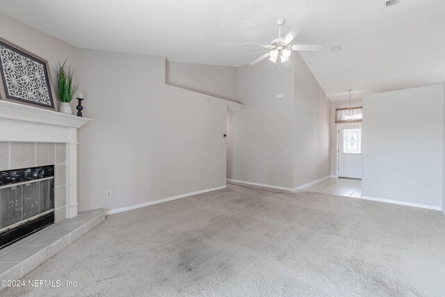 unfurnished living room with light carpet, vaulted ceiling, ceiling fan, a textured ceiling, and a tiled fireplace