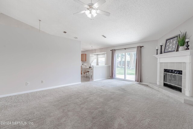 unfurnished living room featuring a fireplace, a textured ceiling, light colored carpet, and ceiling fan