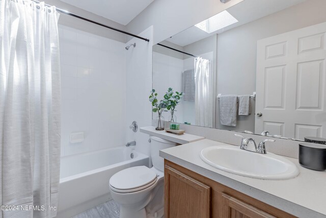 full bathroom featuring a skylight, vanity, shower / bath combination with curtain, and toilet