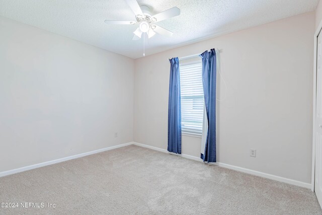 carpeted spare room with ceiling fan and a textured ceiling