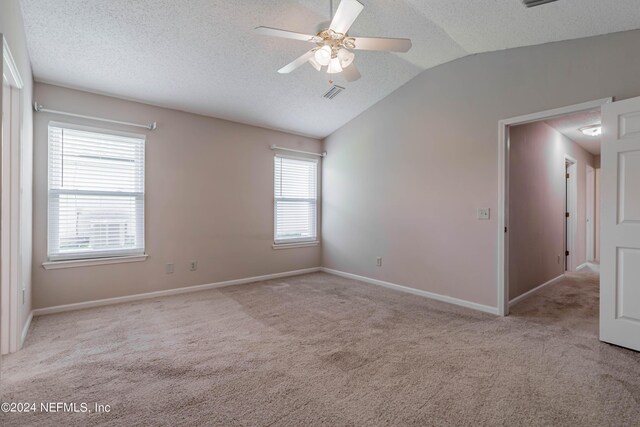 empty room featuring a textured ceiling, ceiling fan, light colored carpet, and lofted ceiling