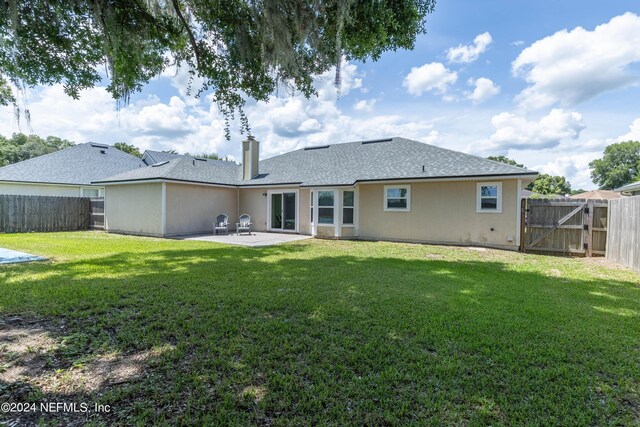 back of property with a yard and a patio