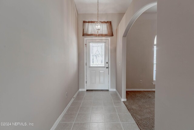 carpeted entrance foyer with a chandelier