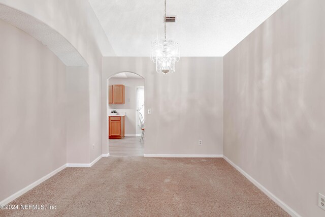 carpeted spare room with a notable chandelier