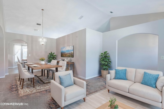 living room featuring light wood-type flooring, an inviting chandelier, and vaulted ceiling