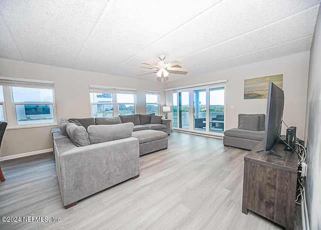 living room with a textured ceiling, ceiling fan, a healthy amount of sunlight, and light wood-type flooring