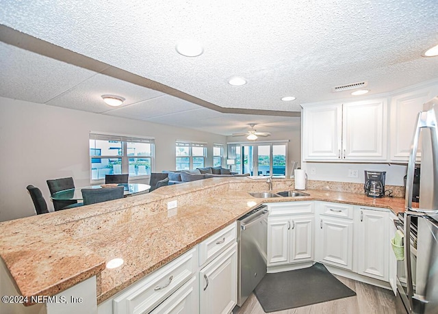 kitchen with stainless steel appliances, white cabinets, ceiling fan, and kitchen peninsula