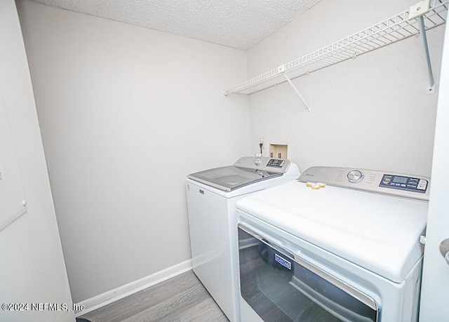 laundry room featuring hardwood / wood-style flooring, a textured ceiling, and washing machine and dryer