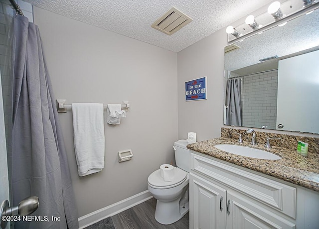 bathroom featuring toilet, hardwood / wood-style flooring, a textured ceiling, a shower with shower curtain, and vanity