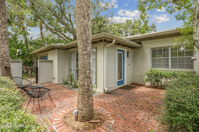 view of exterior entry featuring a patio area and stucco siding