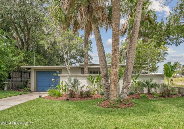 mid-century home featuring a garage, driveway, a front lawn, and stucco siding