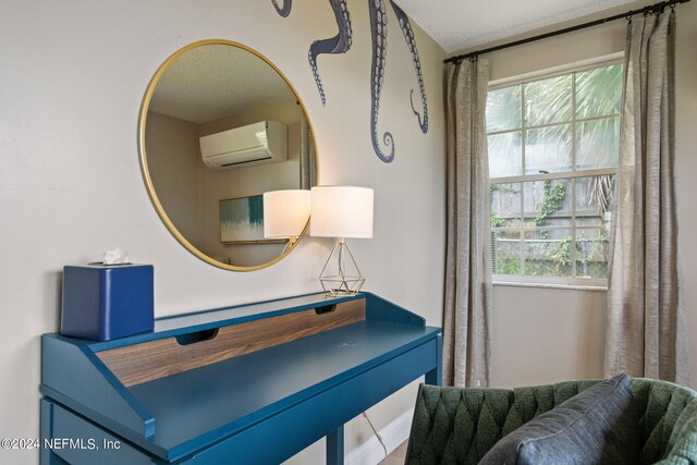 sitting room featuring an AC wall unit and a textured ceiling