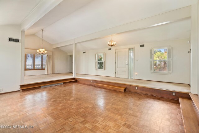 spare room featuring vaulted ceiling with beams, a wealth of natural light, visible vents, and a notable chandelier