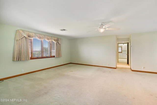 carpeted empty room with baseboards, visible vents, and ceiling fan