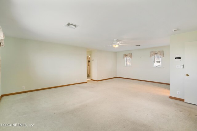 unfurnished room with a ceiling fan, light colored carpet, visible vents, and baseboards