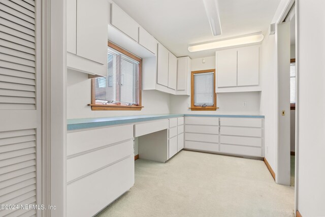 kitchen featuring light carpet, light countertops, white cabinetry, and baseboards