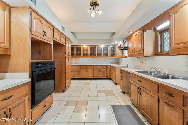 kitchen with oven, a sink, visible vents, brown cabinets, and a tray ceiling