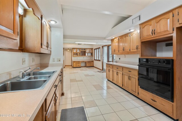 kitchen featuring visible vents, light countertops, vaulted ceiling, a sink, and black oven