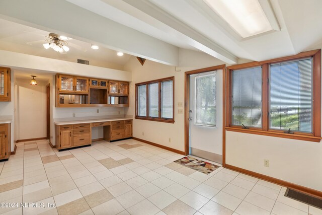 kitchen with lofted ceiling with beams, light countertops, built in study area, and visible vents