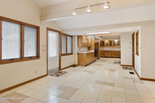 interior space featuring vaulted ceiling with beams, visible vents, baseboards, and light countertops