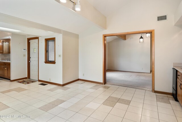 spare room with vaulted ceiling with beams, light tile patterned floors, a sink, visible vents, and baseboards