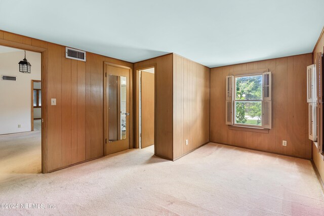 unfurnished bedroom featuring wood walls, carpet, and visible vents