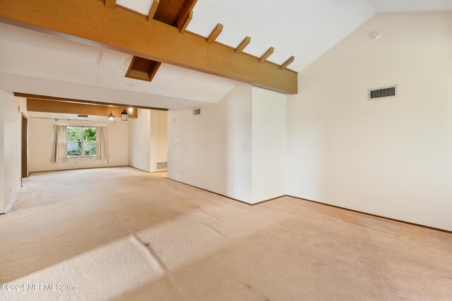 empty room featuring high vaulted ceiling, light colored carpet, and visible vents