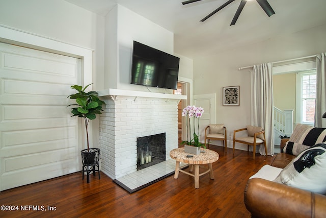 living room with dark hardwood / wood-style floors, a brick fireplace, and ceiling fan