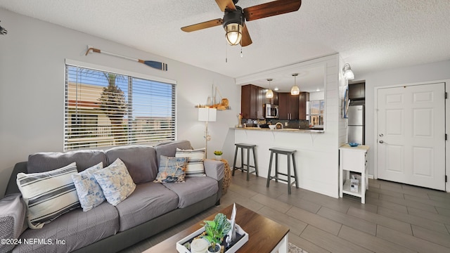 living room with ceiling fan and a textured ceiling