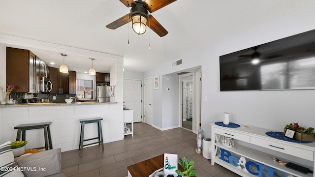 living room featuring ceiling fan and a textured ceiling