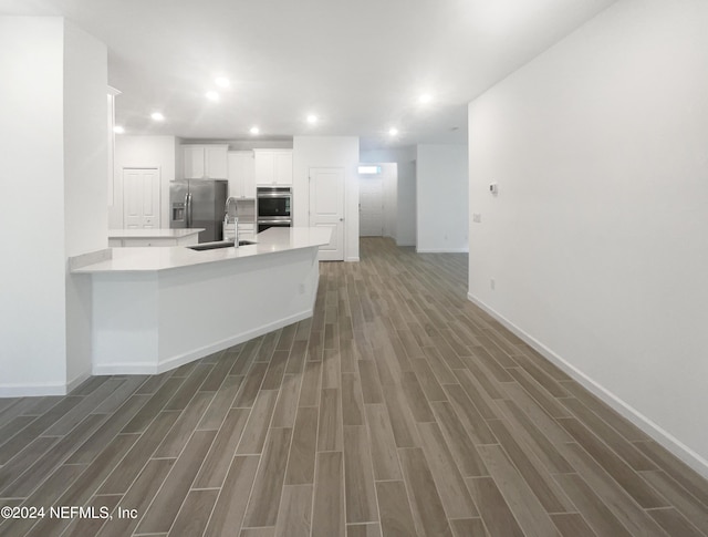 kitchen featuring sink, white cabinetry, kitchen peninsula, dark hardwood / wood-style flooring, and appliances with stainless steel finishes