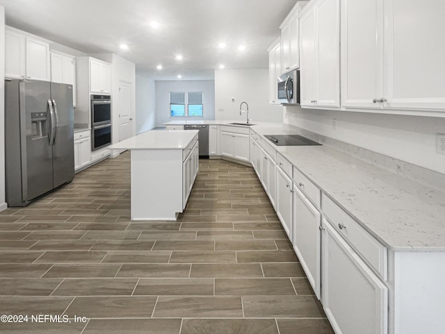 kitchen with kitchen peninsula, a center island, white cabinetry, appliances with stainless steel finishes, and sink