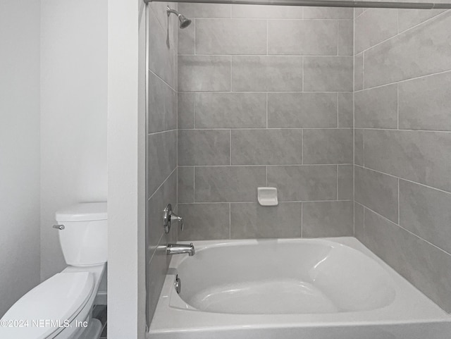 bathroom featuring tiled shower / bath combo and toilet