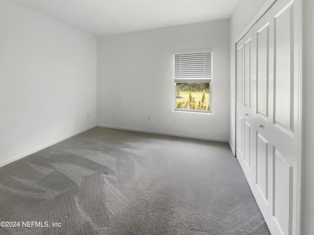 unfurnished bedroom with a closet and dark carpet