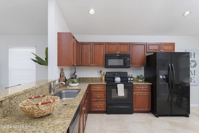 kitchen featuring light stone countertops, sink, light tile patterned floors, and black appliances