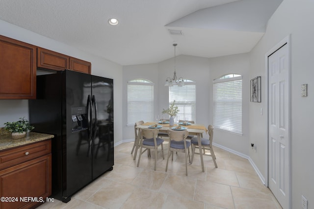 kitchen with pendant lighting, an inviting chandelier, black fridge, light tile patterned flooring, and light stone counters