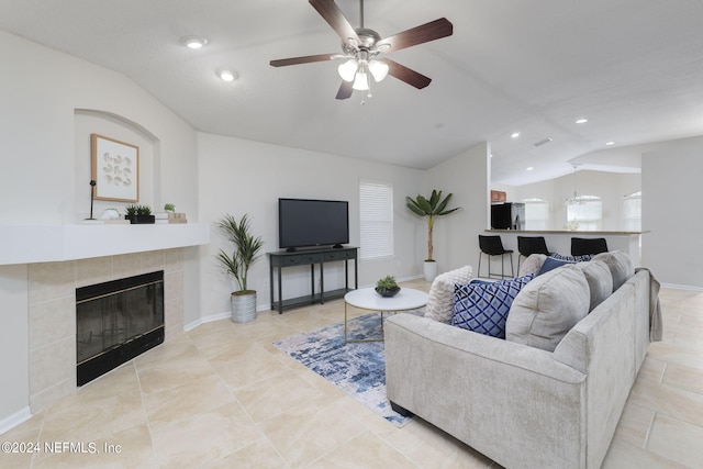 living room with ceiling fan, lofted ceiling, and a tile fireplace