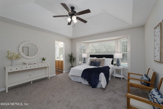 carpeted bedroom with multiple windows, ensuite bathroom, a raised ceiling, and ceiling fan