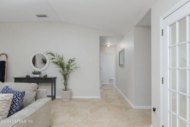 corridor featuring light tile patterned floors and vaulted ceiling