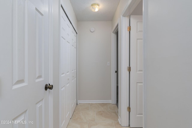 corridor featuring light tile patterned flooring and a textured ceiling