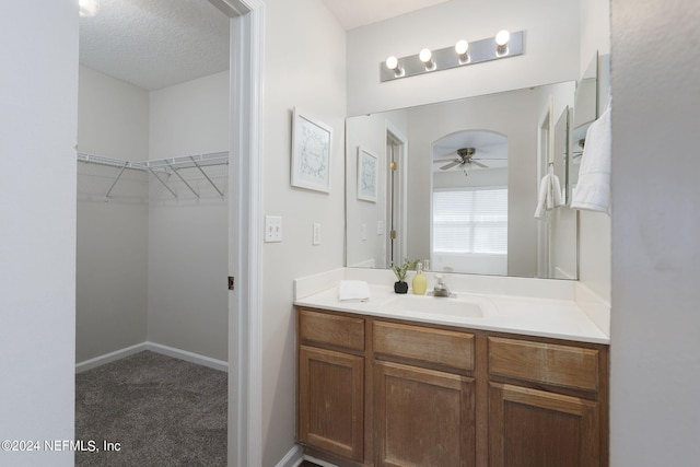 bathroom featuring ceiling fan, vanity, and a textured ceiling