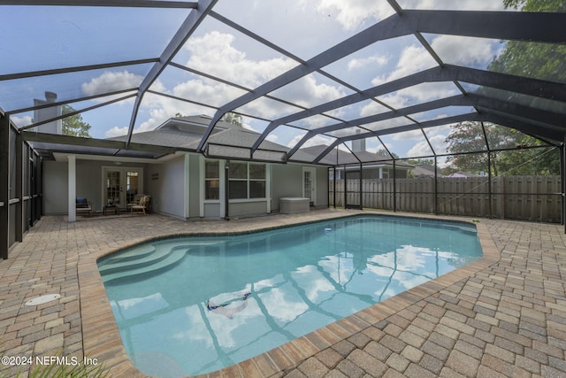 view of pool with glass enclosure, french doors, and a patio