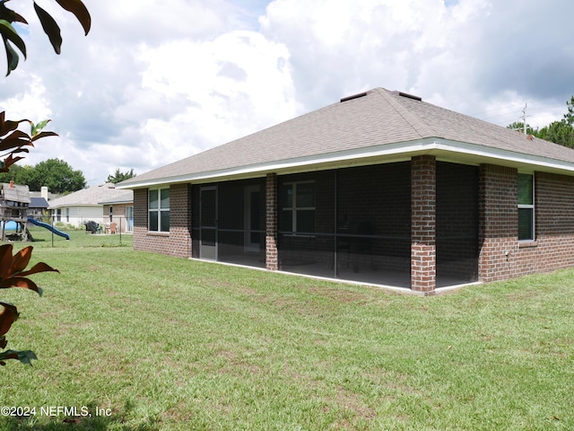 back of house with a playground, a sunroom, and a yard