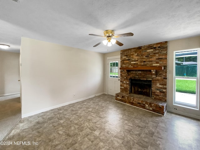 unfurnished living room with ceiling fan, a textured ceiling, and a fireplace